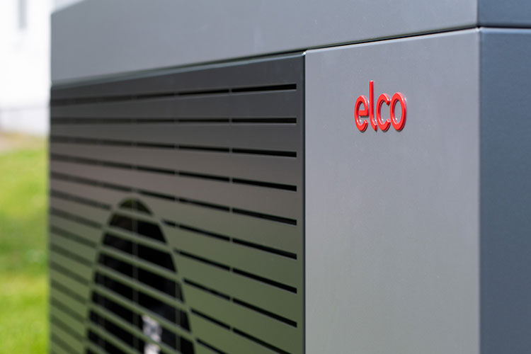 Close-up al unei pompe de căldură aer-apă ELCO, cu logo-ul roșu al companiei și grilajul de ventilație vizibile în exterior.