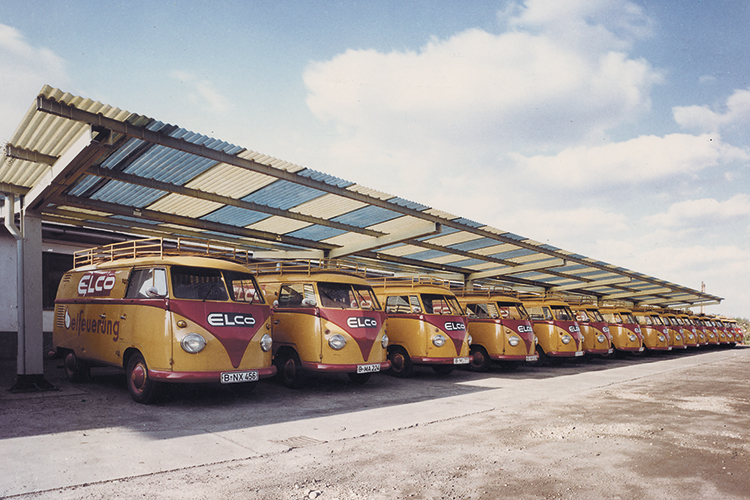 Vehicule de service ELCO de epocă, cu sigla companiei, aliniate în șir în incinta fabricii.